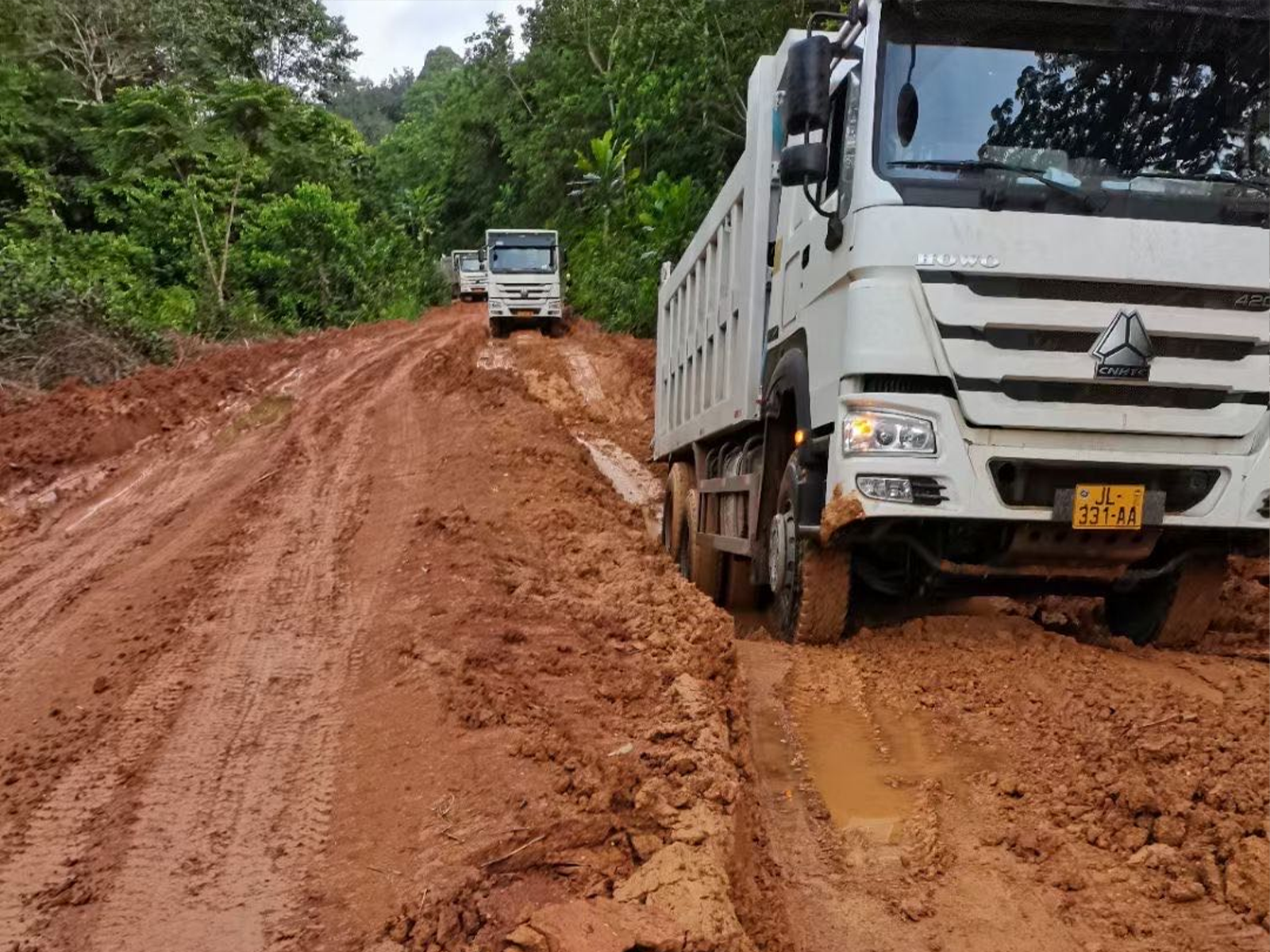 La flotte de camions-benne Sinotruk traverse une route boueuse dans une zone minière.